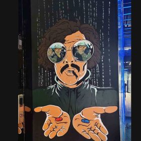Cartoon mural of man with curly hair wearing sunglasses holding a red pill and blue pill.